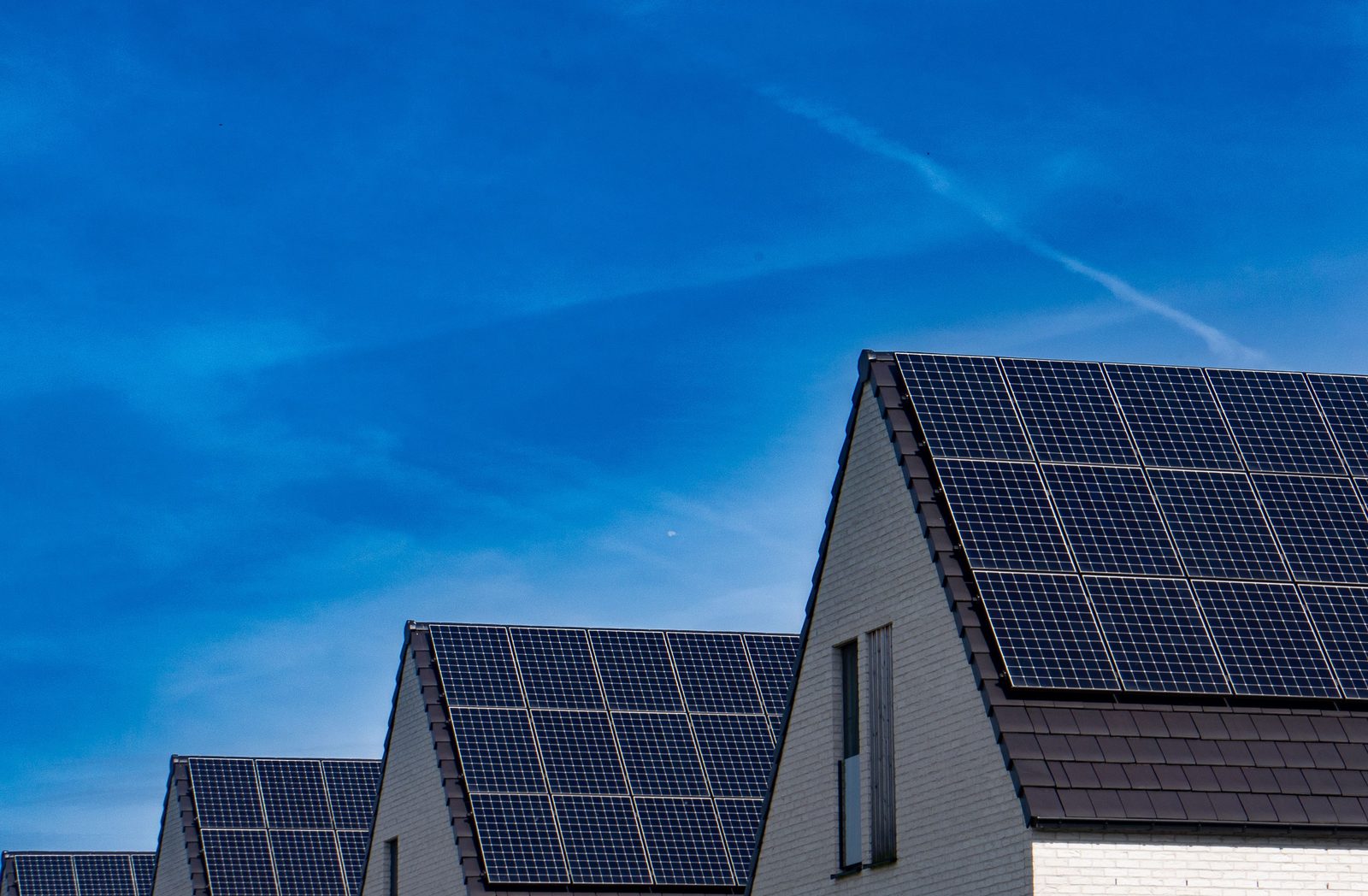 Solar panels on the roofs of modern houses against a blue sky